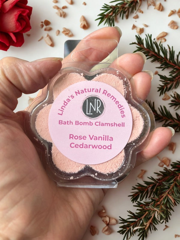 Hand holding a Linda's Natural Remedies bath bomb clamshell with decorative elements on a white background