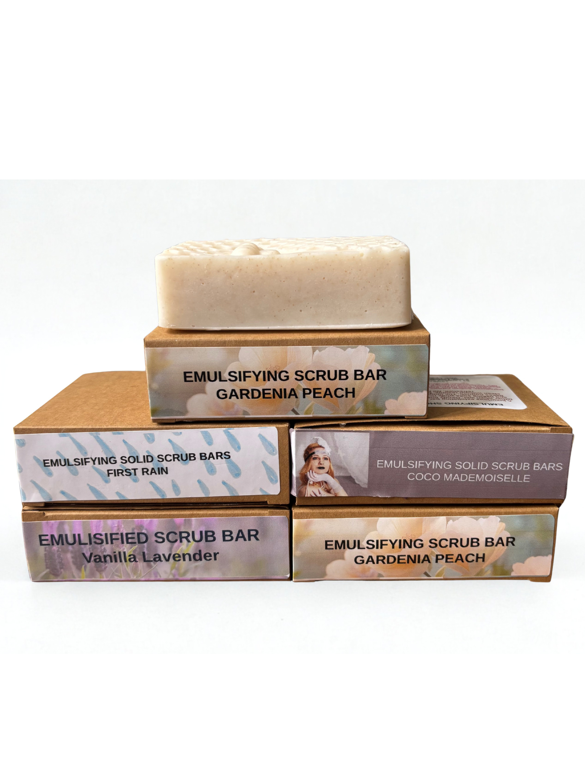 Stack of emulsifying scrub bar boxes with a gardenia peach bar on top against a white background
