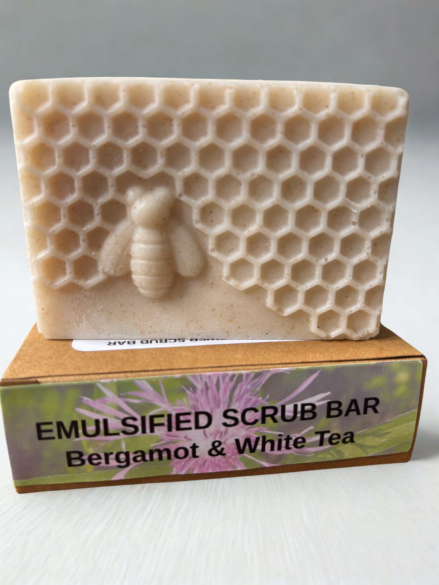 Emulsified scrub bar with honeycomb and bee design on a cardboard box labeled 'Bergamot & White Tea'.