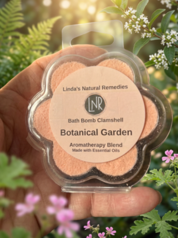 Bath bomb clamshell labeled 'Linda's Natural Remedies' held in front of a natural background with plants and flowers.
