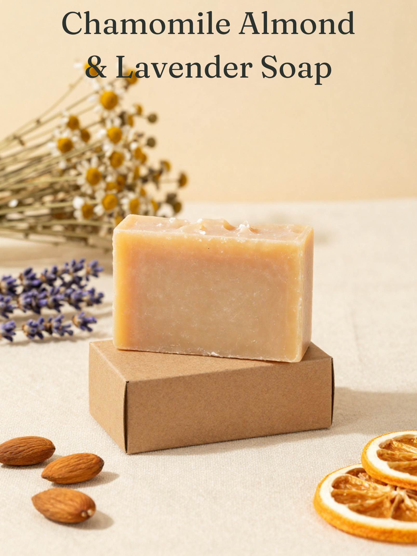 Bar of chamomile almond & lavender soap on a cardboard box with dried lavender, almonds, and orange slices on a light background.