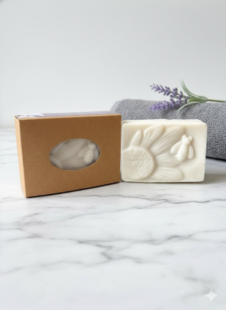 Linda's Natural Remedies Coco Mademoiselle Emulsifying Solid Scrub Bar with artisan kraft paper gift box on a white marble surface with lavender accents.