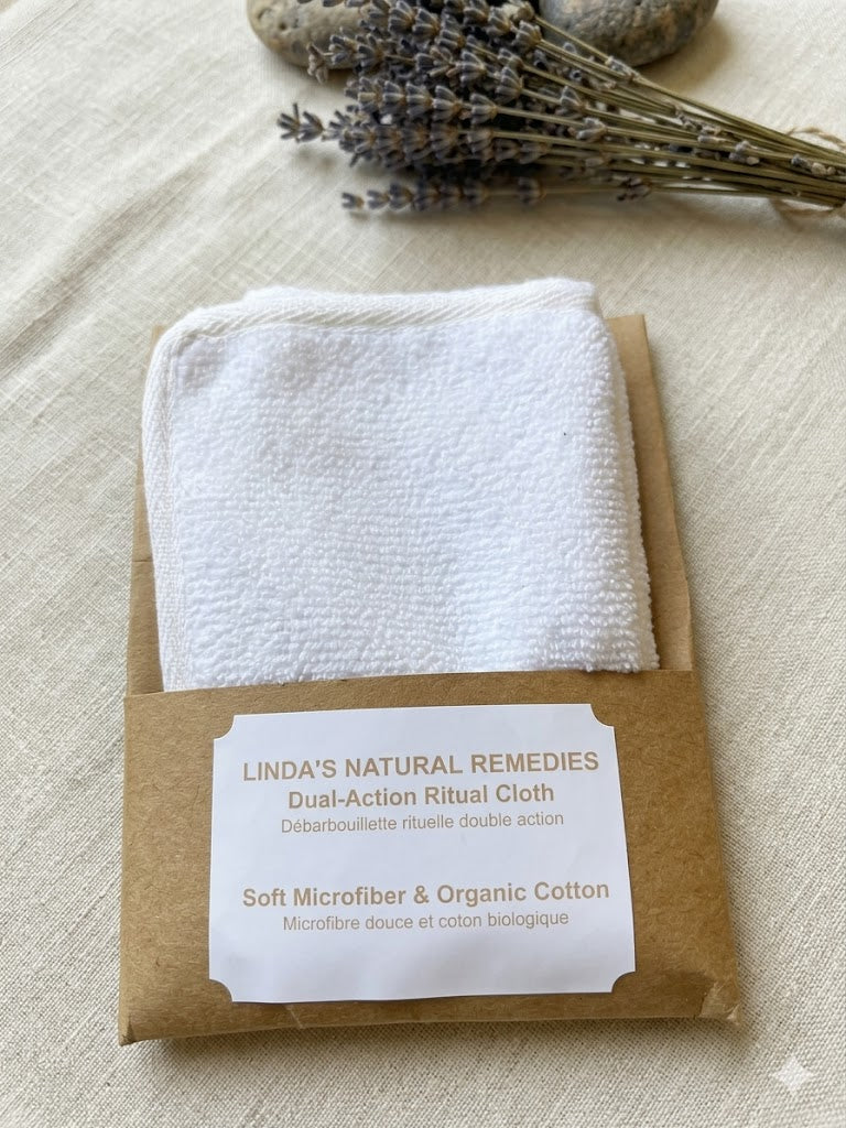 White Dual-Action Ritual Cloth in a kraft paper sleeve with a white label, featuring organic cotton and microfiber textures, styled on a neutral linen background with dried lavender and smooth stones.