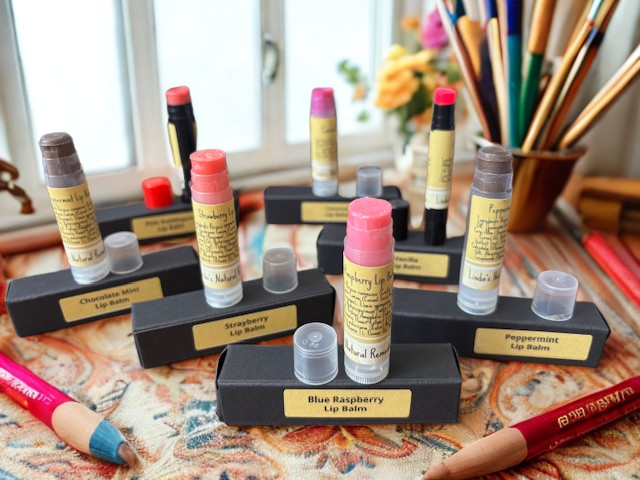 Handcrafted natural lip balm tube displayed open on a black gift box, featuring Linda's Natural Remedies logo and premium botanical ingredients.