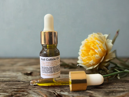 "Linda's Natural Remedies Nail Cuticle Oil in a clear glass dropper bottle, showing the beautiful natural blue-green tint from infused blue tansy and lavender oils."