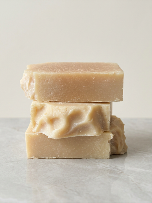 Three bars of soap stacked on a marble surface with a light background