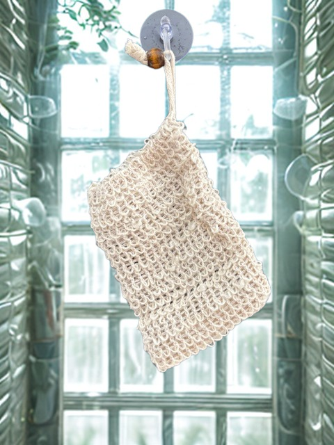 A natural cream-colored organic sisal soap bag with a wooden bead drawstring, designed to save soap scraps and provide gentle skin exfoliation.