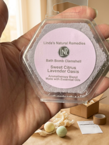 Bath bomb clamshell labeled 'Linda's Natural Remedies' held by a hand.