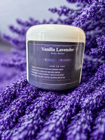 A jar of Linda's Natural Remedies Vanilla Lavender Body Butter nestled in a bed of fresh purple lavender flowers.