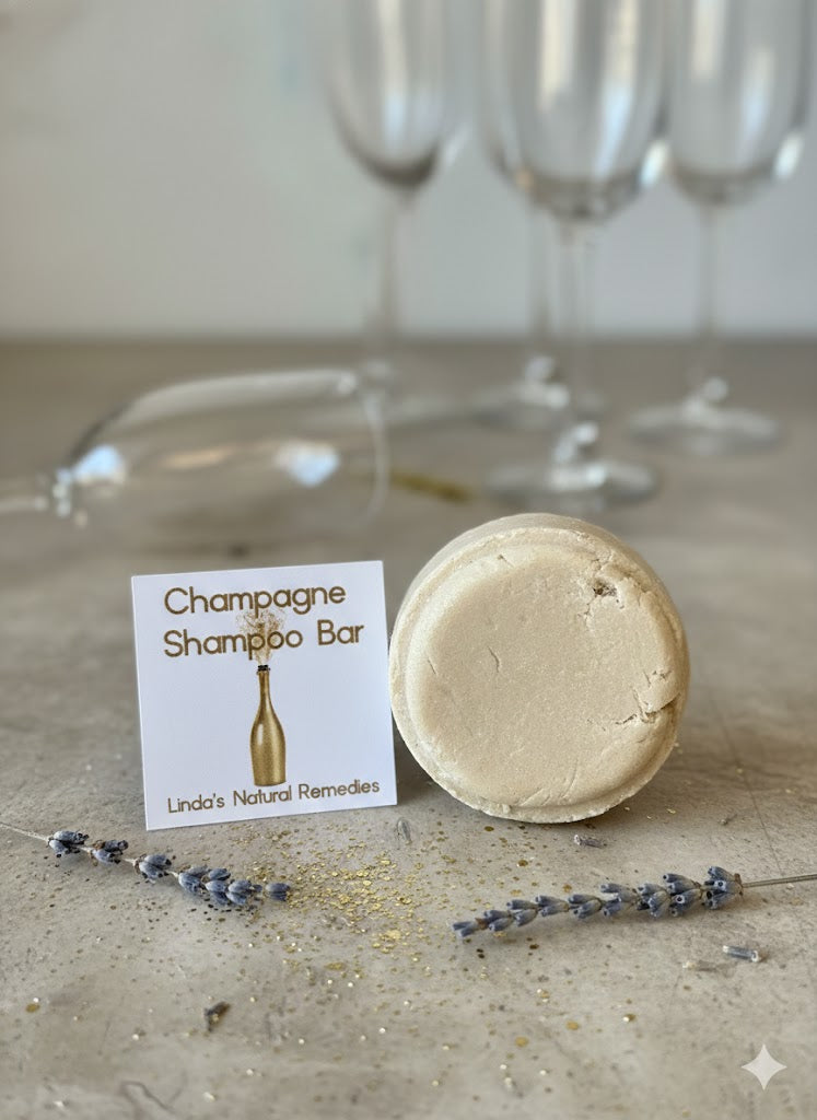 Elegant cream-toned round shampoo bar with gold-toned labels and champagne glass accents.