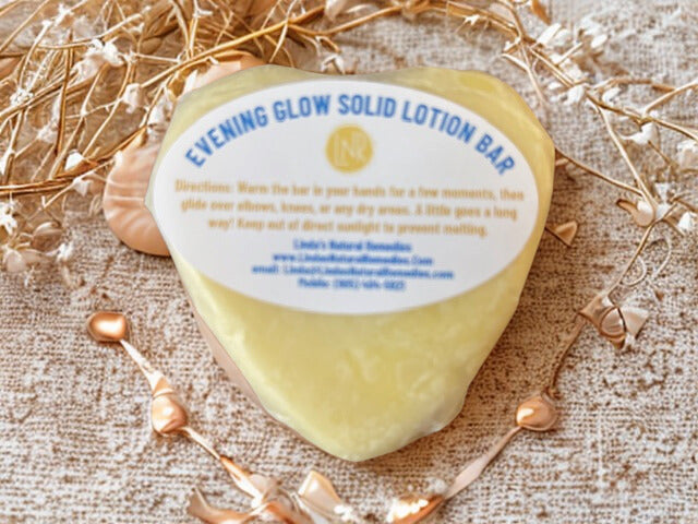 Hand-packaged Evening Glow solid moisturizer heart. The 90g botanical lotion bar is wrapped in sustainable wax paper with a professional scent label.