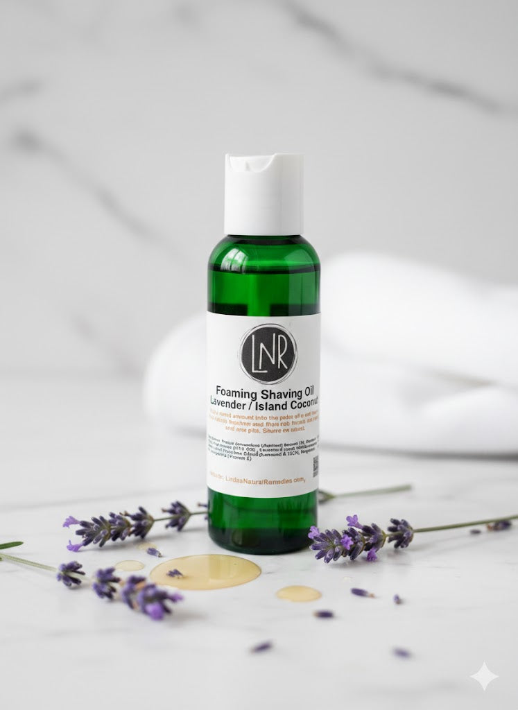 A green bottle of Lavender / Island Coconut Foaming Shaving Oil with a black cap. The product is displayed in a bright, clean setting on a marble surface, highlighting the dual-scent profile of calming lavender and tropical coconut.