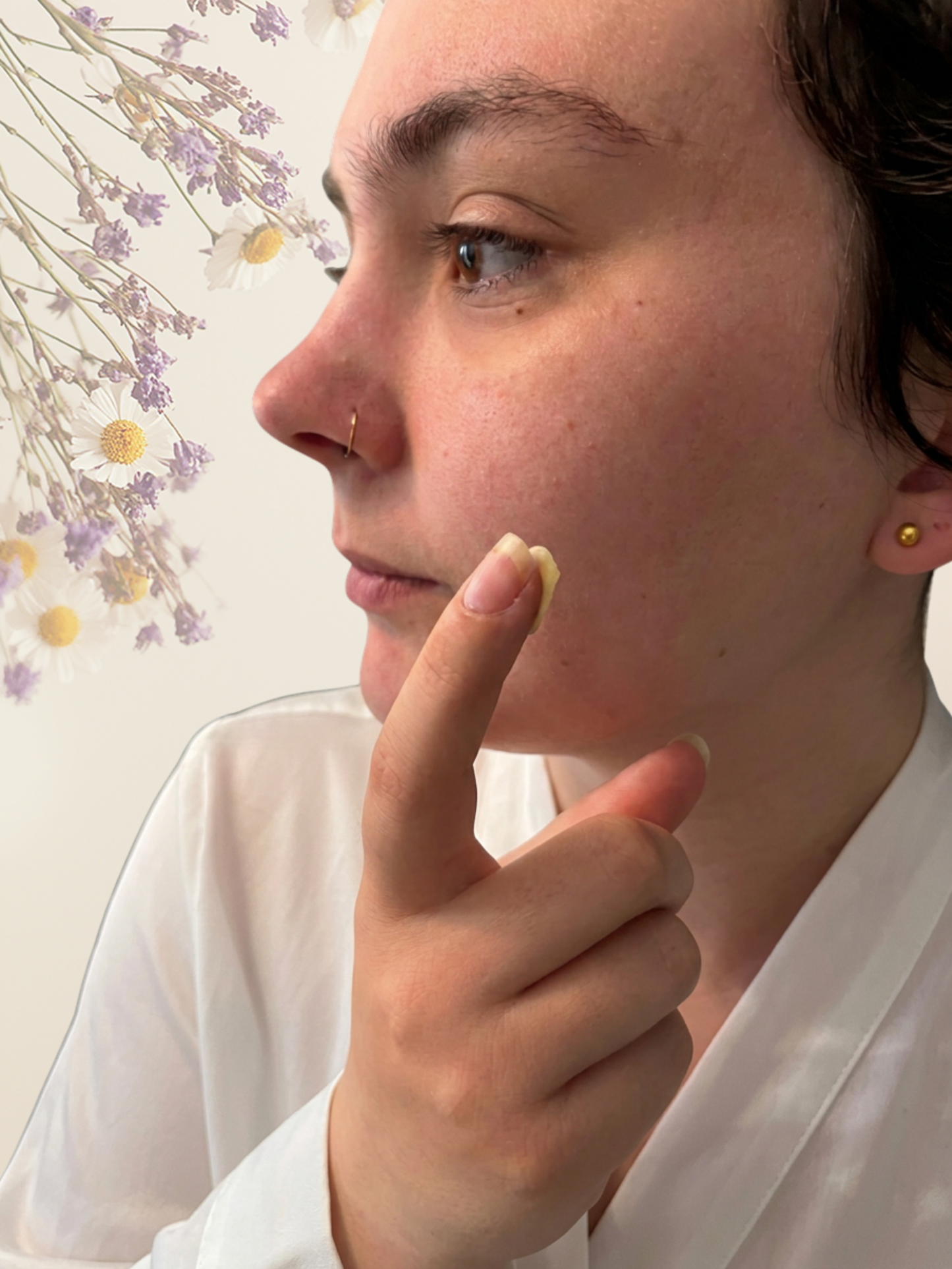 Person wearing gold hoop earrings with a floral background