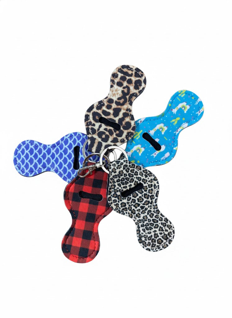 "A selection of patterned lip balm holders, including leopard print and plaid, representing the surprise variety for the Dealer's Choice option."
